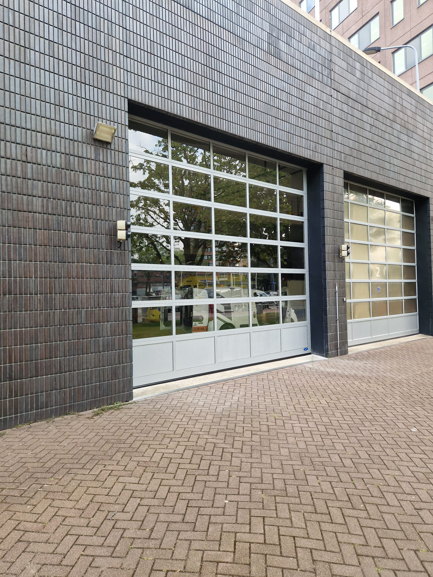 glazen overheaddeur geplaatst bij bedrijfspand met moderne uitstraling